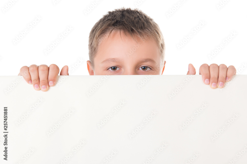 Smiling handsome boy male teenager posing behind white panel on white background. Advertising space for billboard poster Smiling handsome boy male teenager posing behind white panel on white background. Advertising space for billboard poster