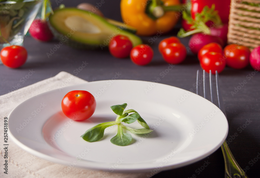 Green fresh leaves with tomato cherry on a white plate. Healthy food. Green fresh leaves with tomato cherry on a white plate. Healthy food.