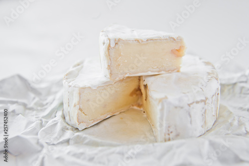 Camembert cheese on white paper. White background, side view, close-up