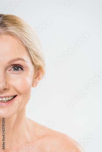 partial view of smiling mature woman looking at camera isolated on grey