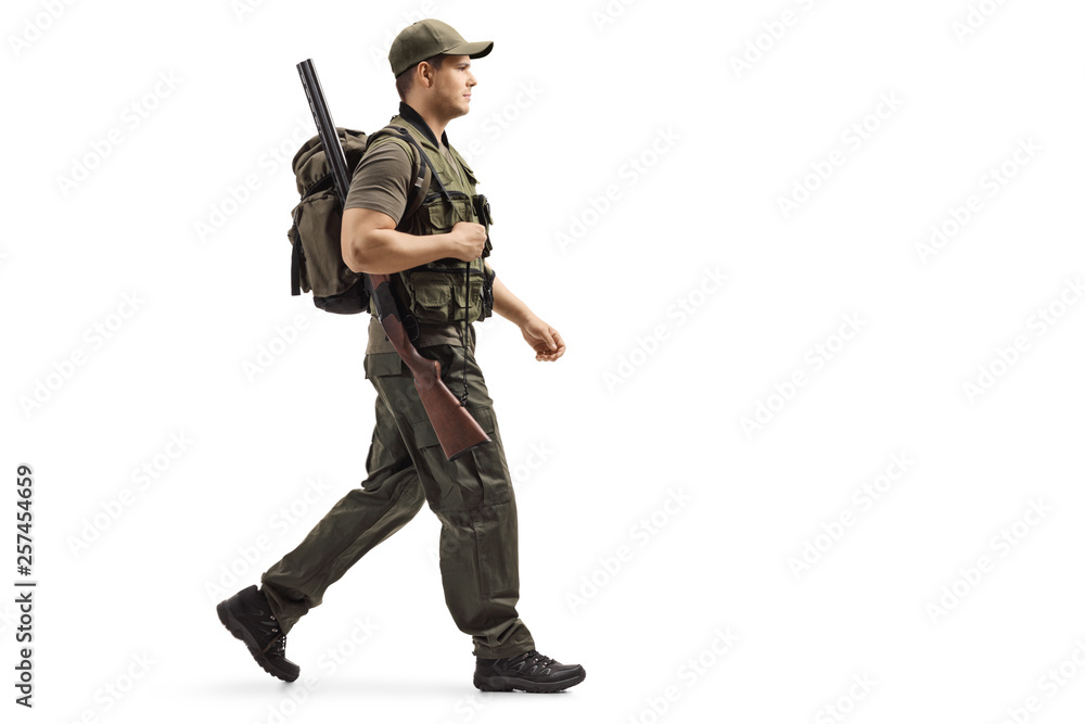 Hunter walking and carrying a backpack and a shotgun Hunter walking and carrying a backpack and a shotgun