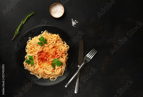 Appetizing Italian pasta spaghetti with tomato sauce, Parmesan cheese on a plate against a background of stone. Top view, with copy space.