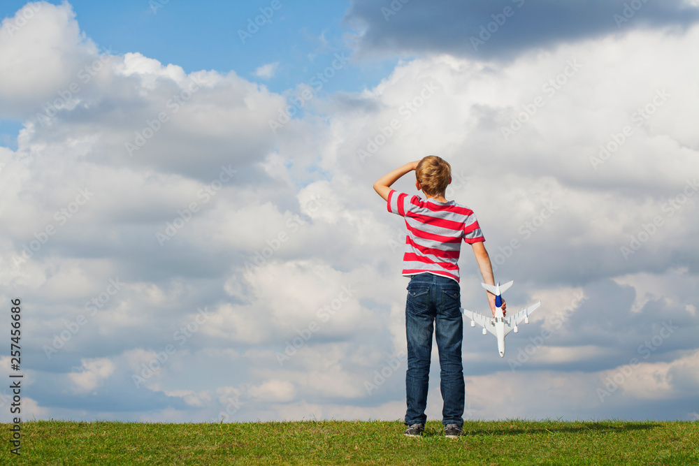 Boy holding model plane looking up to the sky