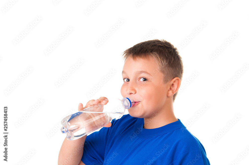 Child drinks clean water from bottle isolated on white background.The boy is wearing a blue T-shirt Child drinks clean water from bottle isolated on white background.The boy is wearing a blue T-shirt