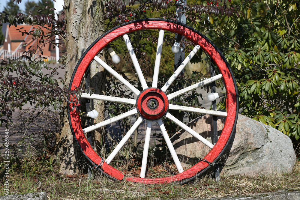 Altes Wagenrad mit roter Lackirung an einem Zaun