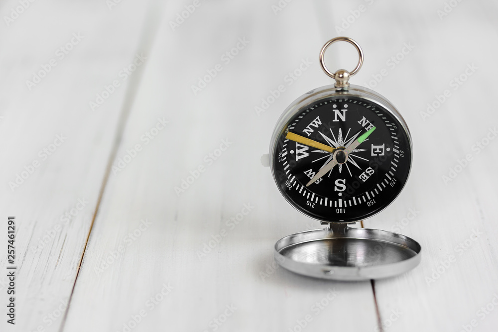 Compass on white wood table over white brick background with copy space. Compass on white wood table over white brick background with copy space.