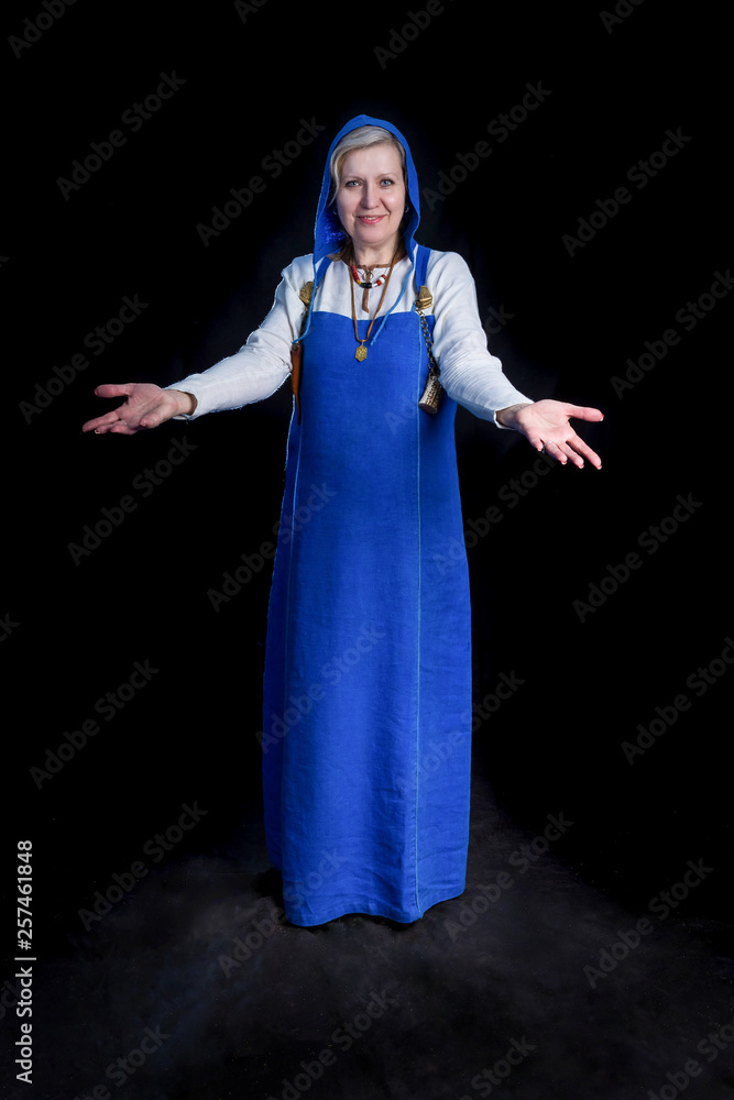 Naklejka premium Mature woman in blue Viking Hangerok dress making welcome gesture