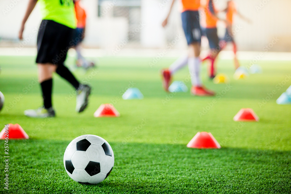 football on green artificial turf with blurry soccer team training football on green artificial turf with blurry soccer team training