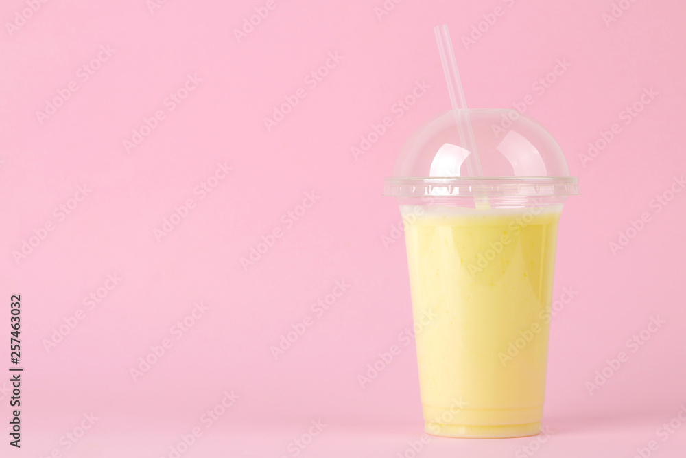 Making a milkshake. plastic disposable glass with a banana milkshake on a bright trendy pink background. space for text Making a milkshake. plastic disposable glass with a banana milkshake on a bright trendy pink background. space for text