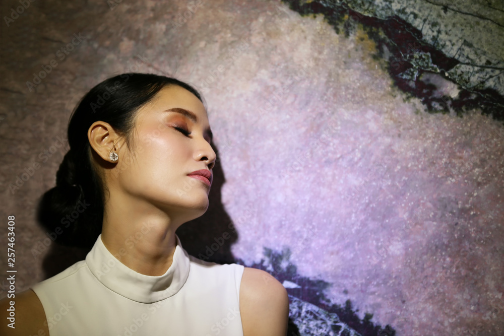 portrait of a thinking young woman standing by wall