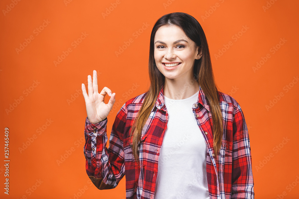 Young happy cheerful woman showing ok sign isolated against orange background. Young happy cheerful woman showing ok sign isolated against orange background.