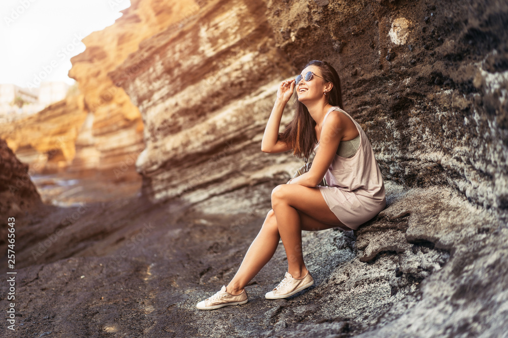 Pretty long hair brunette tourist girl relaxing on the stones near sea. Pretty long hair brunette tourist girl relaxing on the stones near sea.