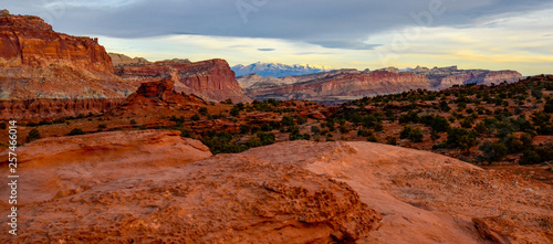 Sunset during golden hour in Southern Utah, sun warming red sandstone, cliffs, mountains, and mesa