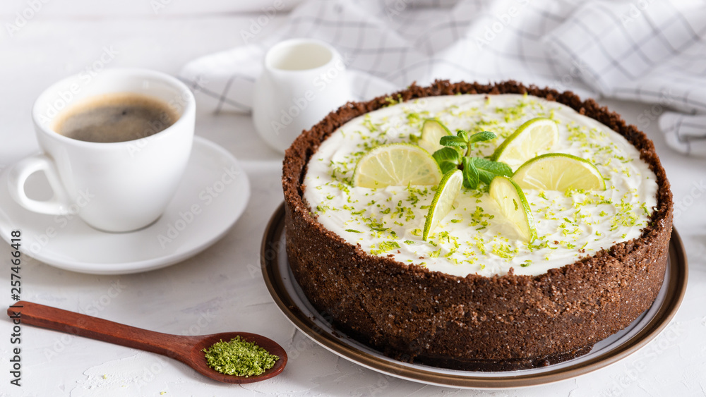 Lime cheesecake with peppermint. Cheesecake with cup of coffee on white background. Side view. Coffee house, confectionery concept, for banner Lime cheesecake with peppermint. Cheesecake with cup of coffee on white background. Side view. Coffee house, confectionery concept, for banner