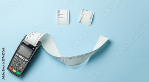 Terminal cash register machine POS for payments and long roll paper cash tape in the shape of smile on blue background. photo