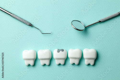 Photos Healthy white teeth and  tooth with caries on green mint background and dentist tools mirror, hook