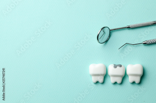 Healthy white teeth and tooth with caries on green mint background  and dentist tools mirror, hook. Copy space for text. © adragan