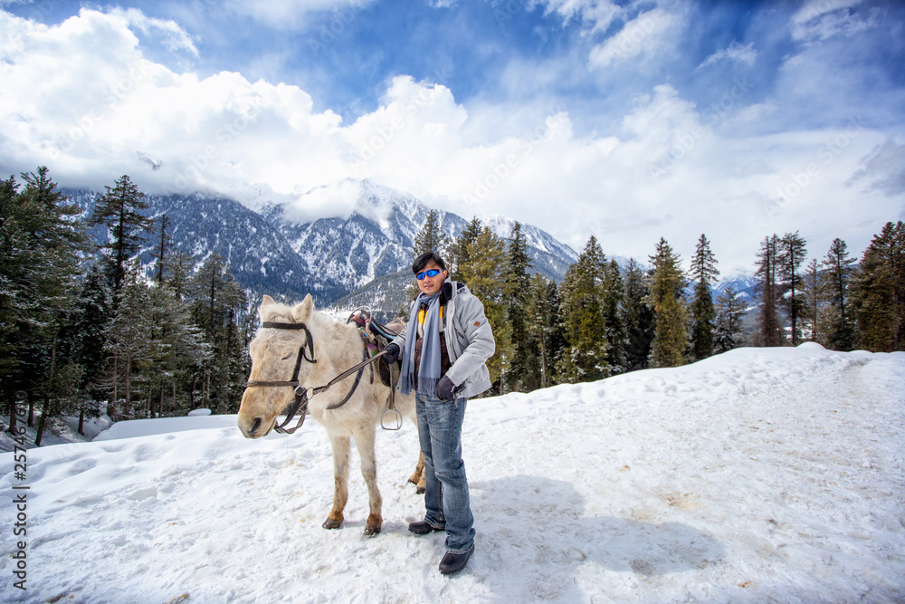 asian man and horse standing on top of snowmountain in winter