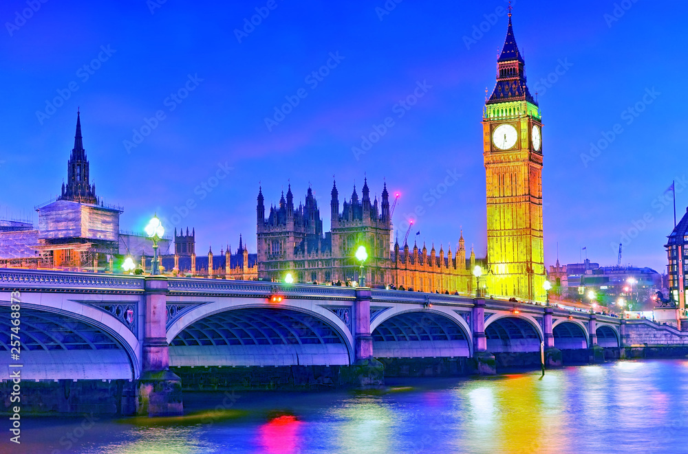 Naklejka premium View of the Houses of Parliament and Westminster Bridge along River Thames in London at night.