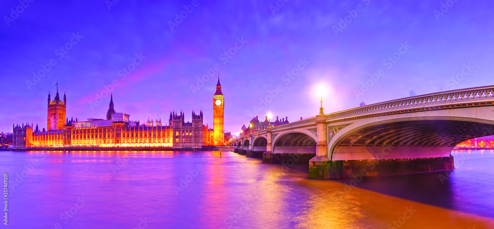 Naklejka premium View of the Houses of Parliament and Westminster Bridge along River Thames in London at night.