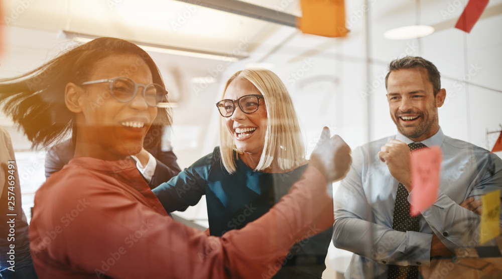 Businesswomen celebrating while brainstorming with their team in Businesswomen celebrating while brainstorming with their team in