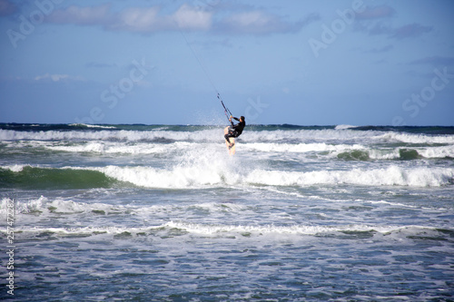 Male kitesurfer jumps the wave on his board in Cardiff-by-the-sea, CA. photo