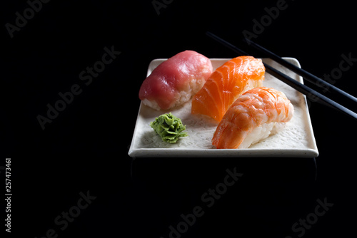 Macro shot of sashimi, uramaki and nighiri, Japanese dish consisting of rice, salmon or tuna, shrimp in black . Concept of Japanese restaurant