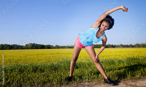 A young woman stretches before running on a dirt trail next to a field of wild flowers in Demopolis, Alabama. photo