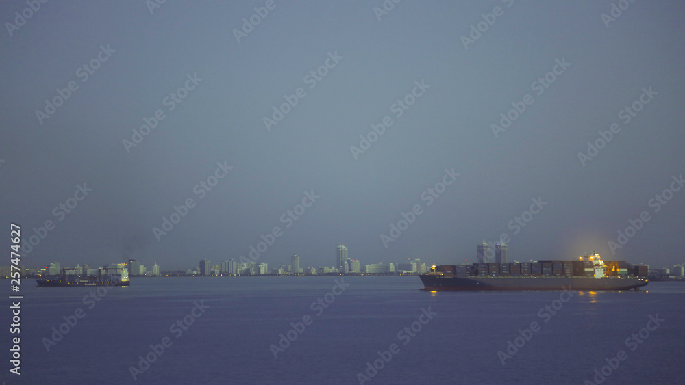 Waterfront of cargo ships and panorama of Miami in night