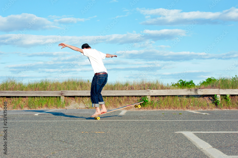A man rides his longboard by the beach. A man rides his longboard by the beach.