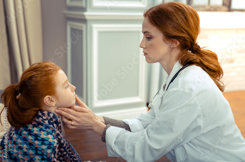 Serious professional therapist checking her patients health
