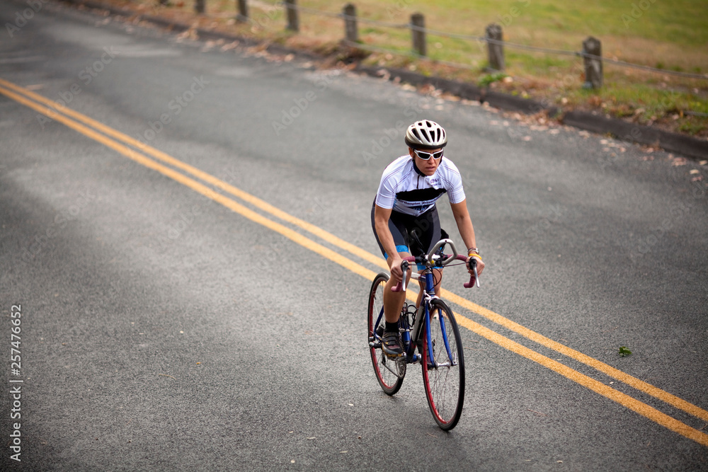 A female cyclist stomps on the pedals while climbing a hill on a ride. A female cyclist stomps on the pedals while climbing a hill on a ride.