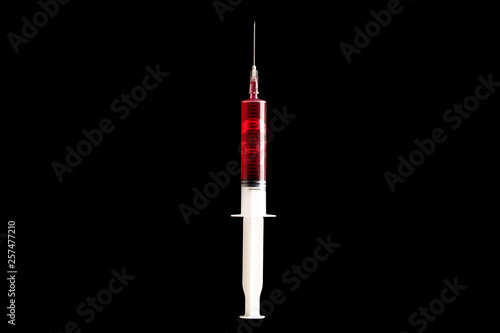 Syringe with blood and skull inside isolated on black, close up. Medical syringe filled with red liquid. Hard drug overdose and addiction concept.