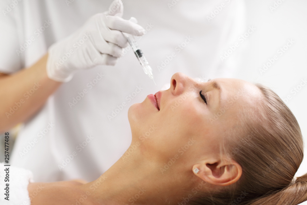 Close up of hands of cosmetologist making botox injection in female lips Close up of hands of cosmetologist making botox injection in female lips