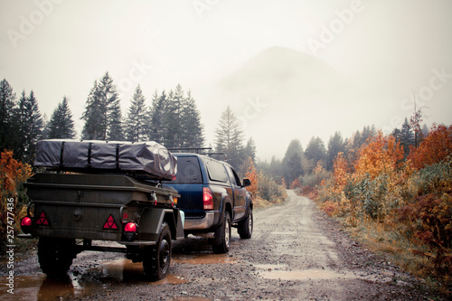 A truck towing a camping trailor drives on a wet gravel foresty road on the west side of Harrison Lake in British Columbia, Canada. photo