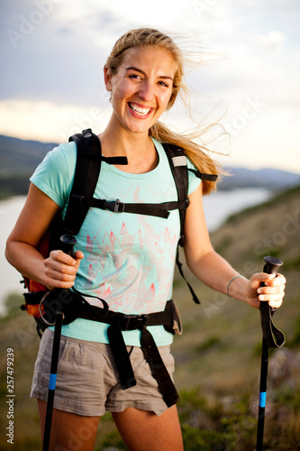 Melissa Lombardi, a young woman, wears a day pack and uses hiking pole as she hikes on windy day along Horestooth Reservoir, Fort Collins, Colorado. photo