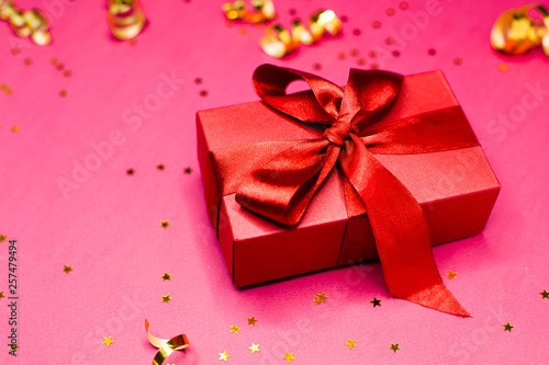 Gift box and Golden decorations and sparkles on bright pink background