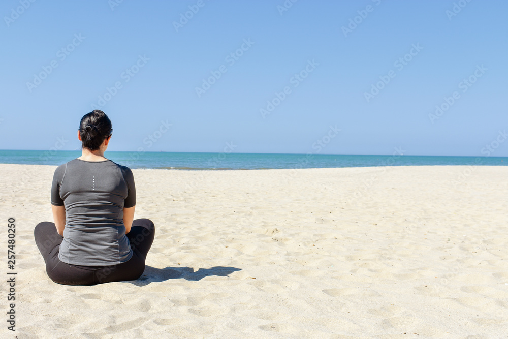 woman sitting on beach and looking at the sea