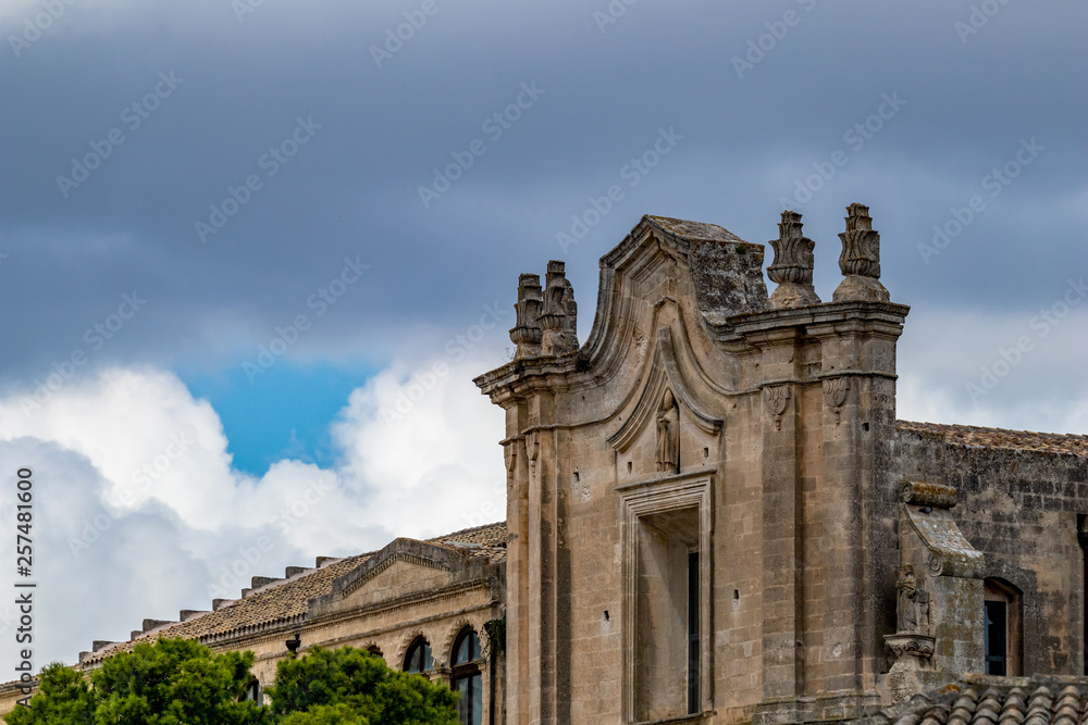 Church tower, roof and entry arch of Chiesa di Sant'Agostino, view of ancient town of Matera, Basilicata, Southern Italy, cloudy summer warm August day
