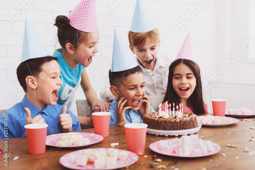 Boy blowing candles on birthday cake  celebrating with friends