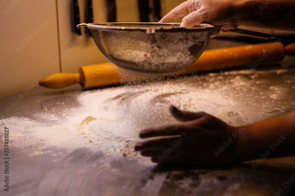 Fototapeta premium The chef mixes the dough from flour and eggs. Smoke flour Sifting flour. Chef's hands. Kitchen processes