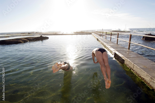 Men dive and swim in ocean rock pool. photo