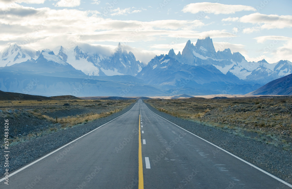 Empty country road amidst field against snowcapped mountains Empty country road amidst field against snowcapped mountains