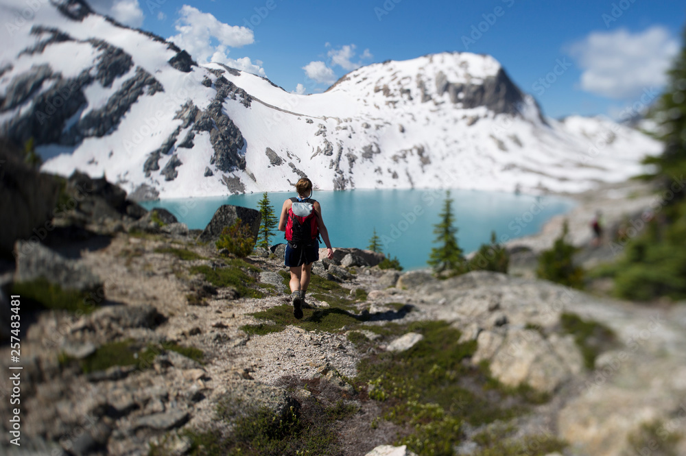 A young woman hiker walks towards a lake. A young woman hiker walks towards a lake.