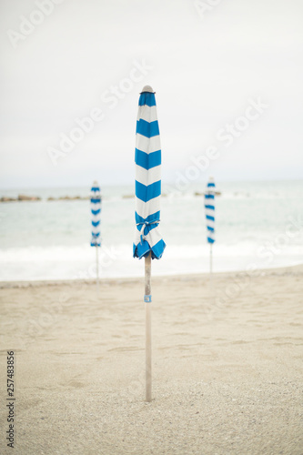 Umbrellas remain closed on an empty Italian beach.