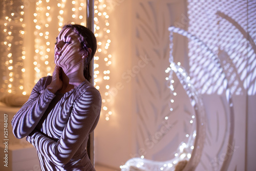 Beautiful young girl with stripes on the body from the projector. Portrait of a girl on the background of garlands