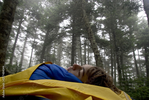 A teenage boy wakes up in a wilderness campsite.