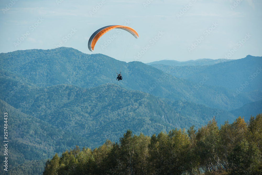 Paragliding in Altai mountains. Paragliders in fight in the mountains, concept of extreme sport activity. Paragliding in Altai mountains. Paragliders in fight in the mountains, concept of extreme sport activity.