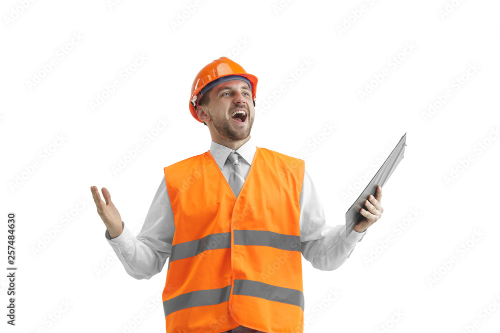 The builder in a construction vest and orange helmet standing on white studio background. Safety specialist, engineer, industry, architecture, manager, occupation, businessman, job concept