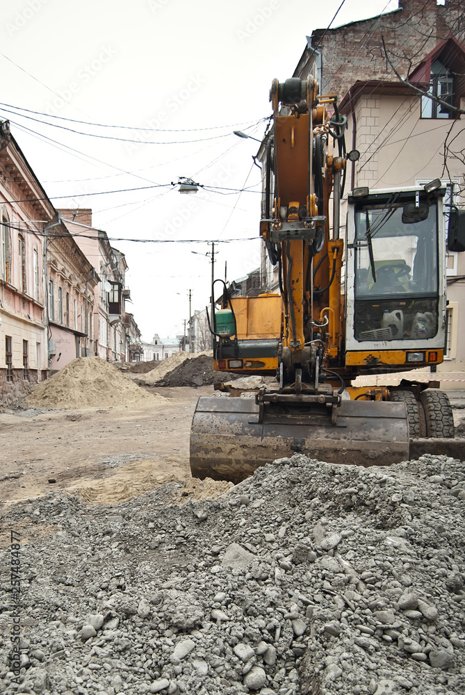 The street of the city is torn down. Construction and laying of pipelines and sewerage. Large excavator in construction. Chernivtsi, Ukraine, Europe, March 2019.